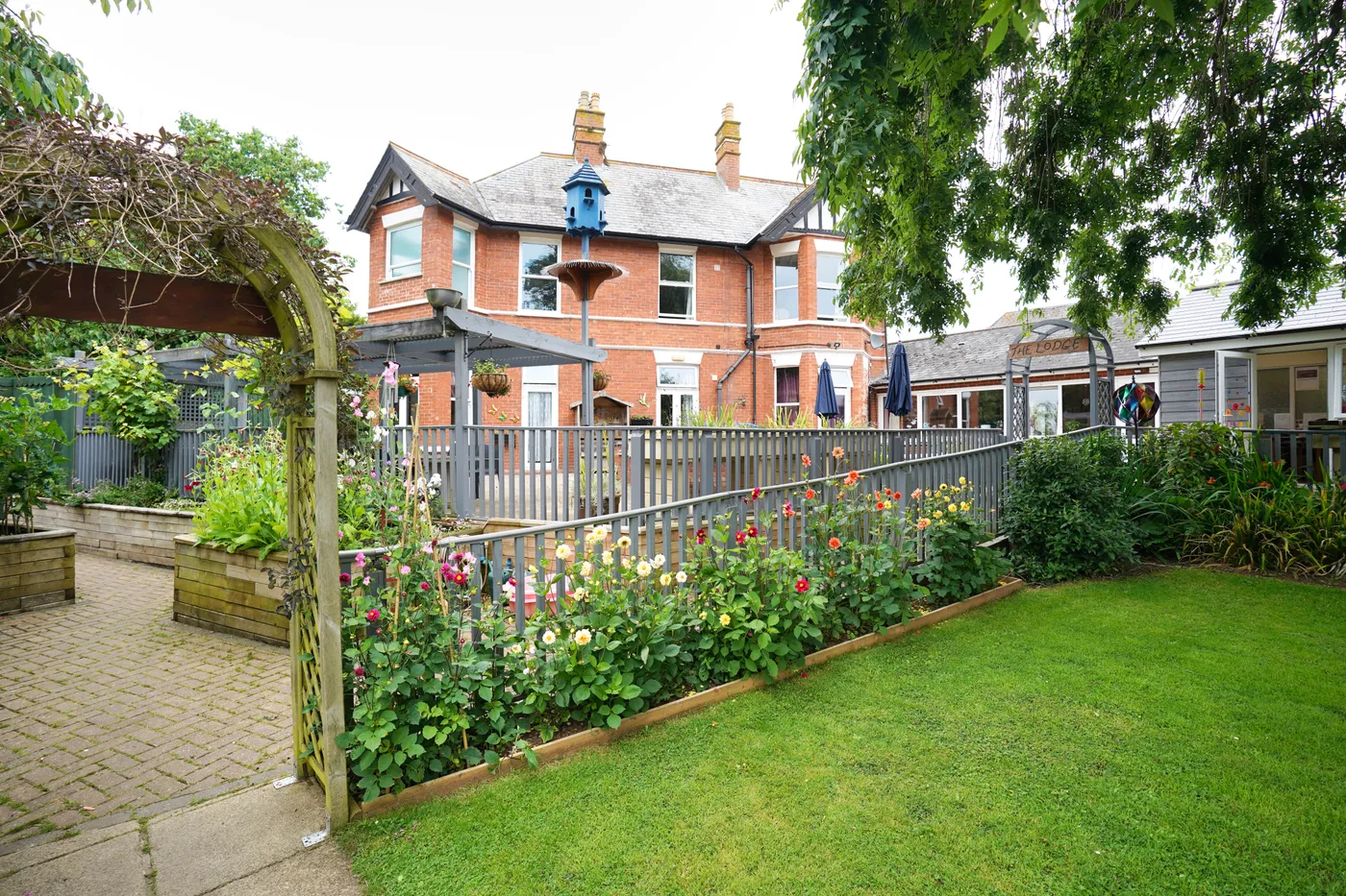 Rose Lodge's red-brick house seen across the lawn and flower borders, with the blue dovecote on the right
