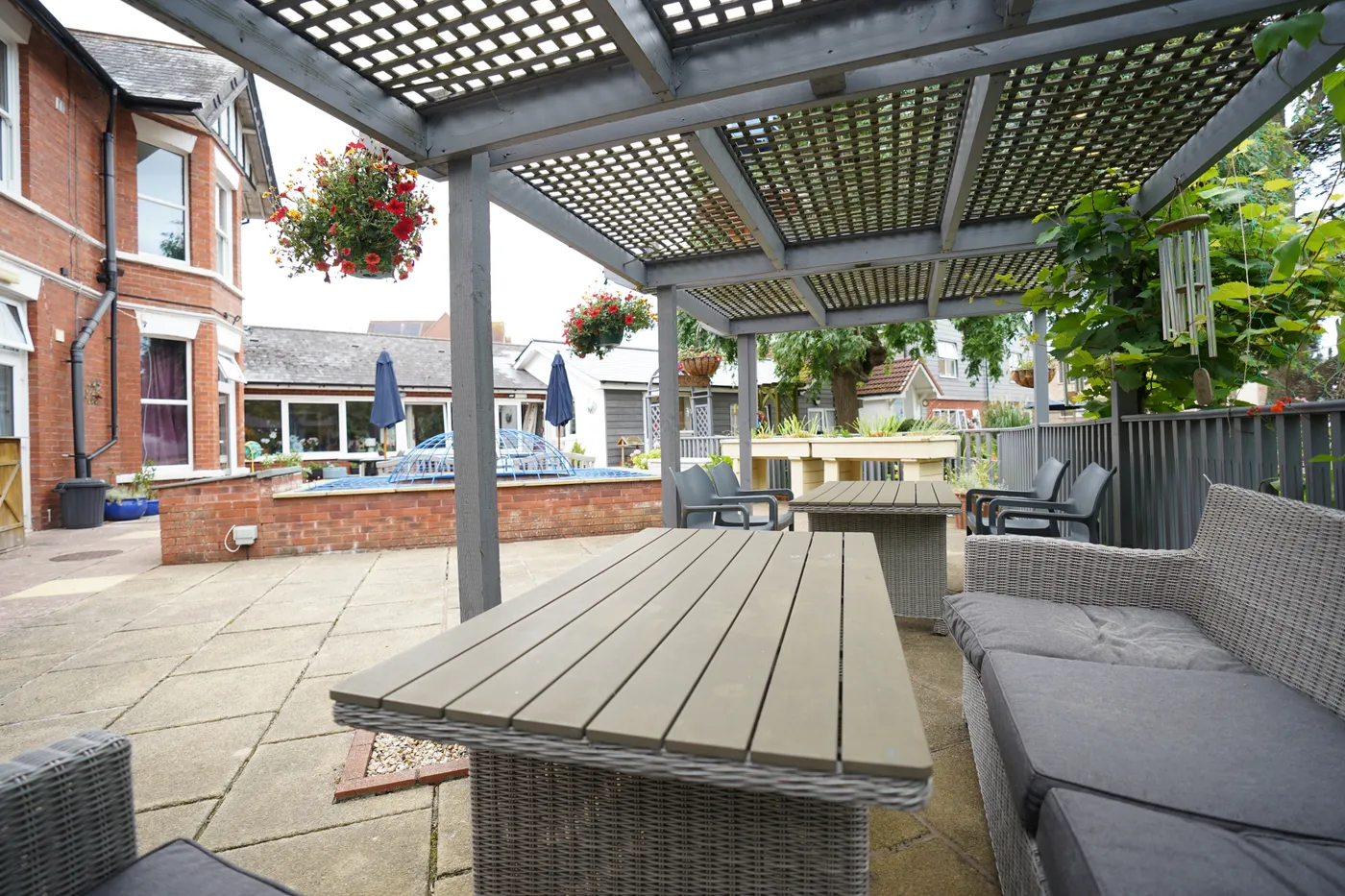 The covered terrace with garden tables, cushioned seating and hanging baskets